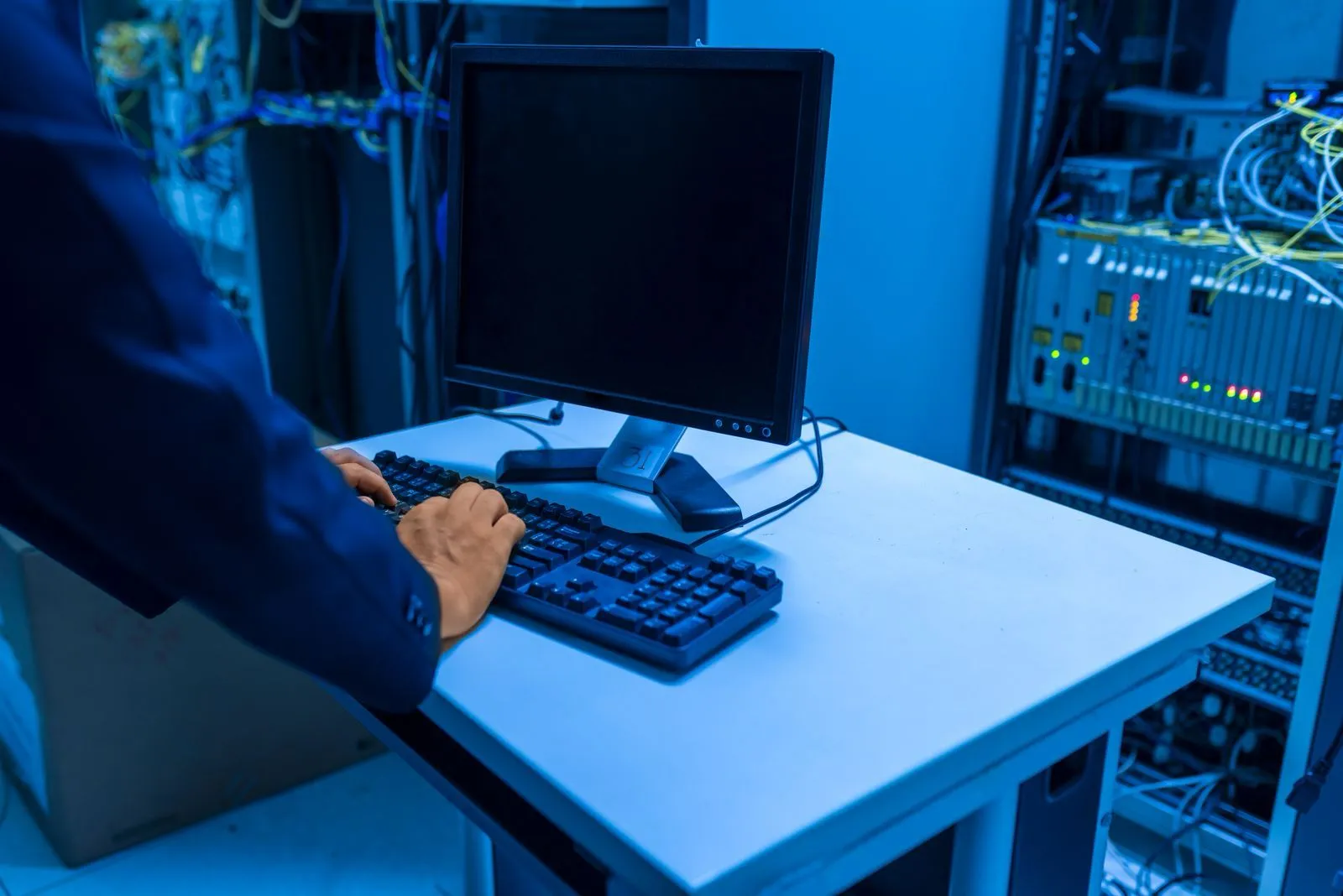 An engineer at a workstation beside a server rack